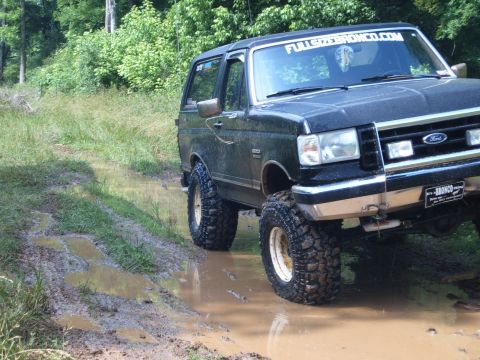 1988 Ford Bronco - This Ford Bronco navigates a muddy trail with its large off-road tires.