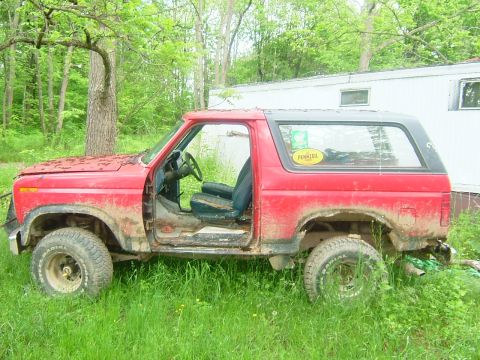1984 Ford Bronco - This red Ford Bronco, likely from the early 1980s, is missing its doors and appears to be in disrepair.