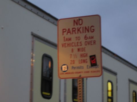 1990 Ford Bronco - orange No Parking sign warns against oversized vehicles between 1am and 6am, photographed against a dusky sky.