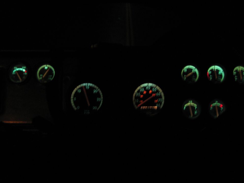 Illuminated vehicle gauge cluster glowing green and red in the dark