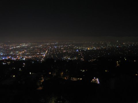 1990 Ford Bronco - vast carpet of city lights stretches to the horizon under a dark sky, viewed from a hillside above.