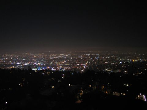 1990 Ford Bronco - Colorful city lights spread across the valley at night, framed by a dark hillside in the foreground.