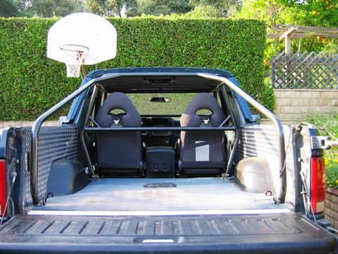1985 Ford Bronco - The interior of a pickup truck is shown, racing seats and a custom roll cage installed.