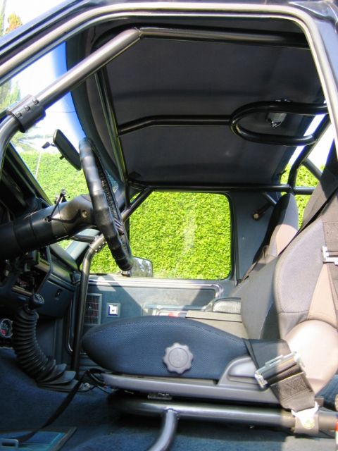 1985 Ford Bronco - The interior of a vehicle is shown, a custom roll cage and racing seat.