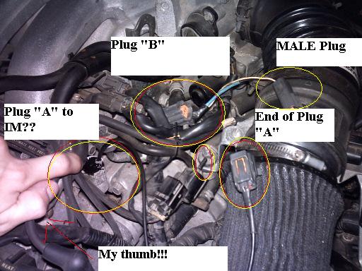 Engine bay with labeled electrical connectors and a hand pointing