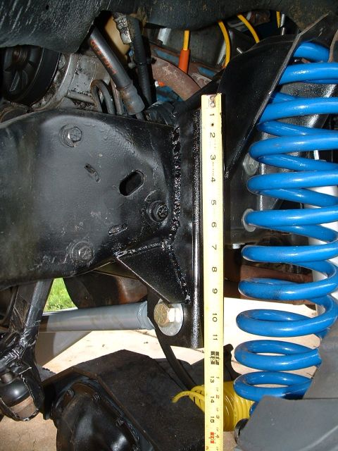 1995 Ford Bronco - A measuring tape is used to show the height of a blue coil spring on a vehicle's suspension system.