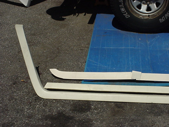 White plastic trim pieces and a tire with 'KELLY' visible, on a blue mat