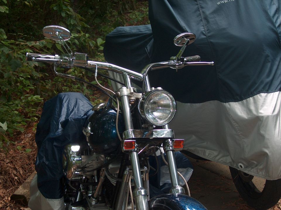 Chrome front end of a blue custom motorcycle, round headlight and pullback bars