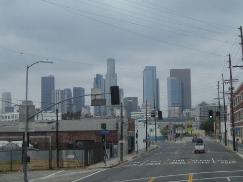 1990 Ford Bronco - View down a wide urban street toward a downtown skyline of high-rise towers under overcast sky, with traffic signals.