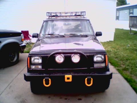 1995 Ford Bronco - A modified Jeep Cherokee XJ is parked in front of a building, with another vehicle partially visible.