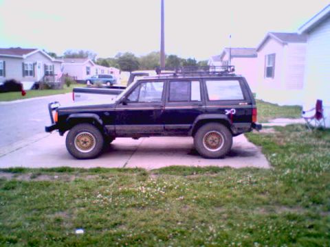 1995 Ford Bronco - This black SUV is parked on a concrete pad in front of a residential building.