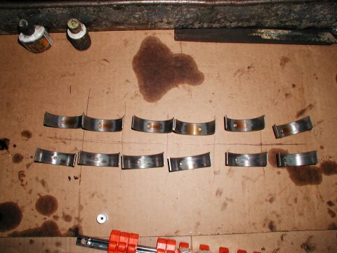1992 Ford Taurus - Engine rod bearings are shown laid out on a surface with oil stains and markings.