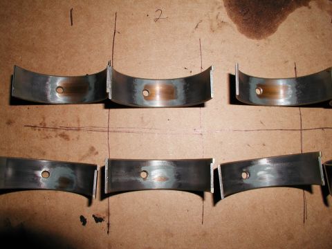 1992 Ford Taurus - Used rod bearings are shown on a cardboard surface, indicating wear and oil staining.