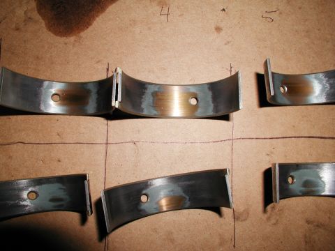 1992 Ford Taurus - Several engine rod bearings are shown laid out on a piece of cardboard, possibly for inspection or replacement.