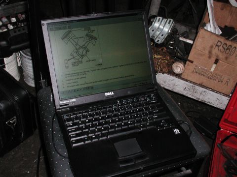 1992 Ford Taurus - Photograph of a Dell laptop on a stool in a garage showing an electronic service manual piston-installation screen; a photo, not a document…