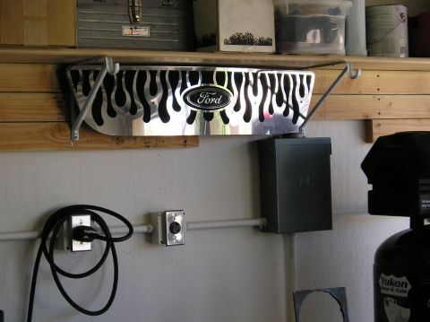 1999 Ford F-150 - A chrome automotive part with flame decals and a Ford emblem is mounted on a wall.