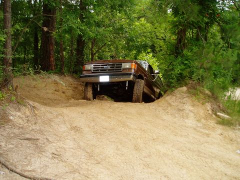 1990 Ford Bronco - Ford Bronco navigating a challenging off-road trail with steep inclines.