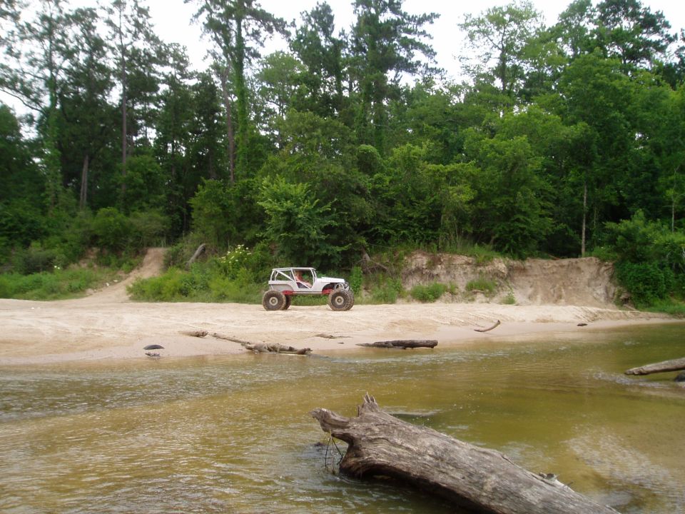 White off-road buggy with large tires on a sandy riverbank