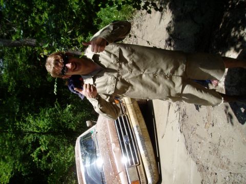 1990 Ford Bronco - Man gives thumbs up next to a muddy Ford truck stuck in the mud.