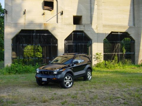 2001 Isuzu Vehicross - A black 2001 Isuzu Vehicross is parked on grass in front of a concrete building.