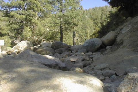 1997 Ford Ranger - A rocky path winds through a wooded area, with a sign visible on the left.