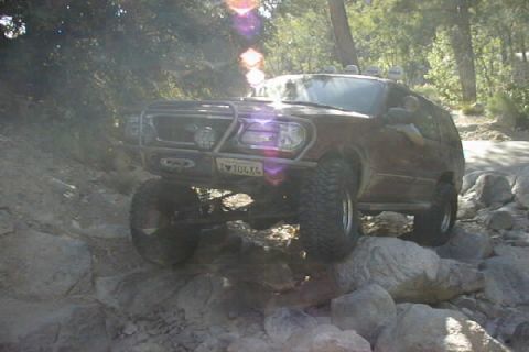 1997 Ford Ranger - SUV navigating a rocky trail, likely off-roading in a wooded area.