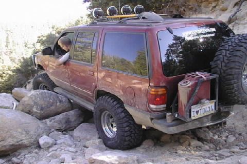 1997 Ford Ranger - This modified SUV navigates a rocky trail, its off-road capabilities with large tires and external fuel storage.