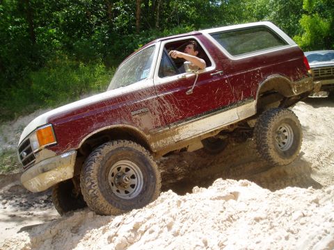 1990 Ford Bronco - 1990 Ford Bronco navigating a challenging sandy incline off-road.
