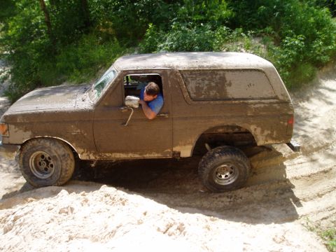 1990 Ford Bronco - A mud-splattered SUV navigates a challenging off-road course.