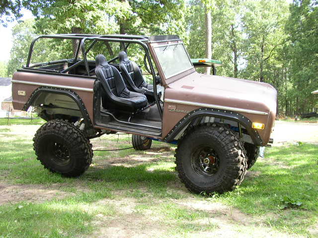 Brown Ford Bronco with roll cage, racing seats, and large tires, 3/4 front view