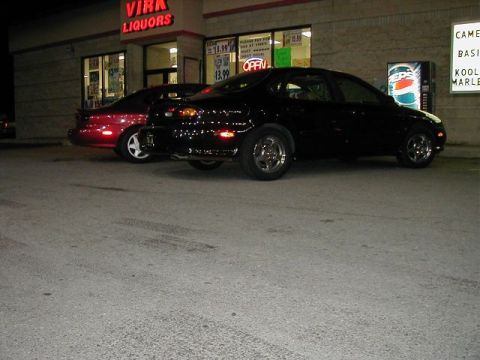 1997 Ford Taurus - Two cars are parked outside a brightly lit liquor store at night, with a Pepsi machine visible.