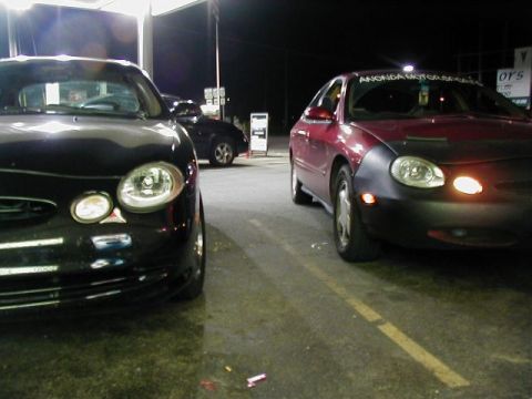 1997 Ford Taurus - Two Ford Taurus sedans are parked next to each other at night.