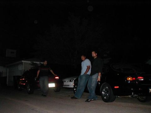 1997 Ford Taurus - Three men pose with cars in a dimly lit outdoor setting at night.