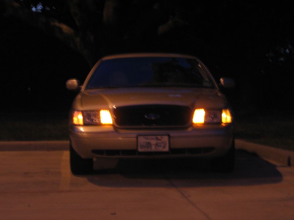Front view of a 2000 Ford Crown Victoria with headlights on at night
