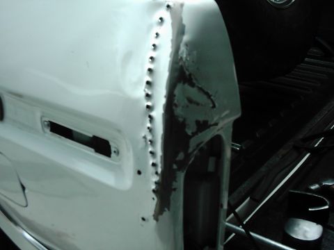 1978 Ford Bronco - The rear quarter panel of a vehicle is undergoing body repair, with visible spot welds along the seam.