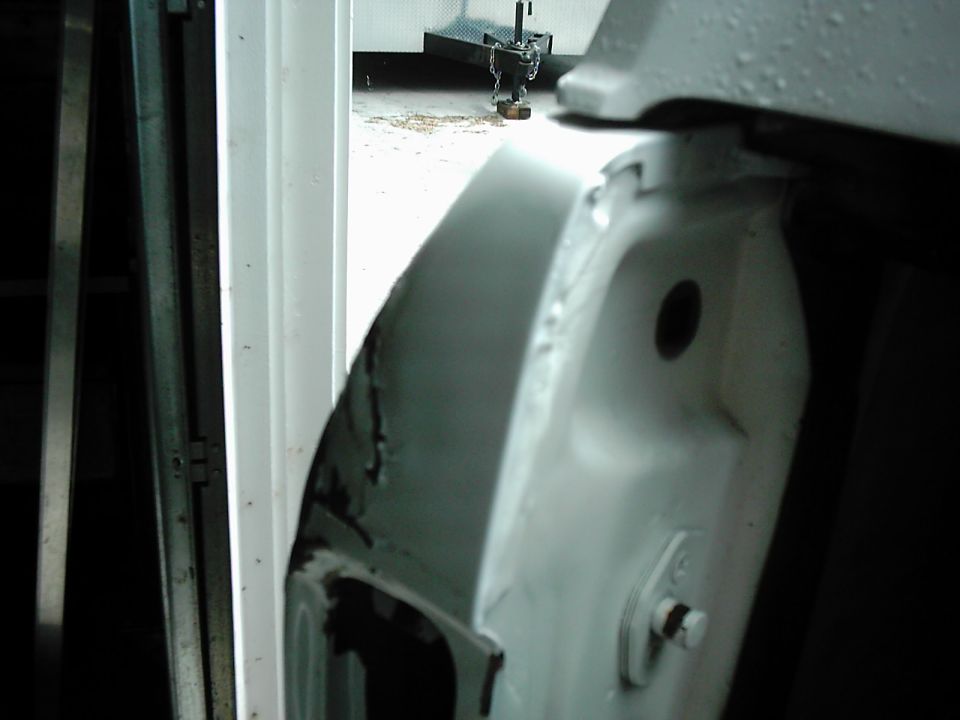 Close-up of a white vehicle door jamb with rust and damage