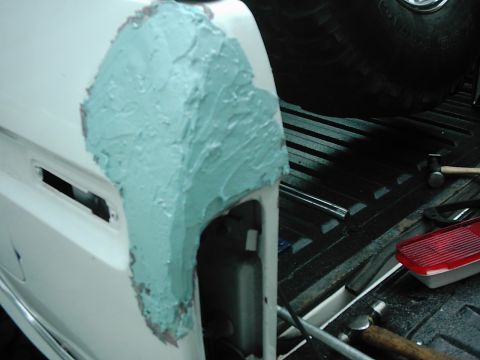1978 Ford Bronco - Body filler is being applied to repair damage on a vehicle's fender.