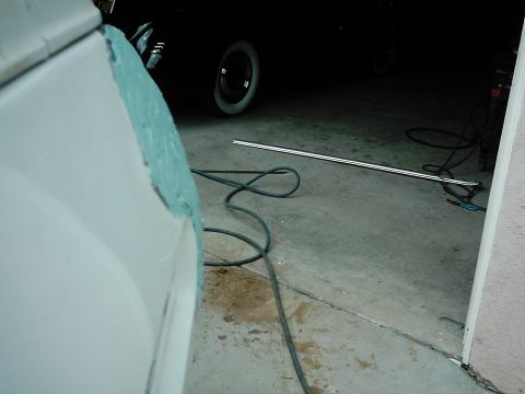 1978 Ford Bronco - A car fender is being prepped for repair with body filler, surrounded by tools and cables in a garage.
