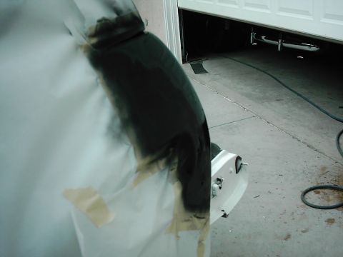 1978 Ford Bronco - A car fender is being masked and spray painted in a garage.