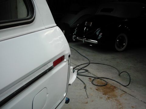 1978 Ford Bronco - Close-up of a white SUV's rear, with a classic car parked behind it in a garage.