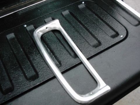 1978 Ford Bronco - A chrome trim piece rests on a black, textured surface, possibly the bed of a truck or SUV.