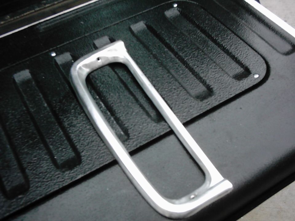 chrome trim piece on black textured surface, likely from a vehicle bed