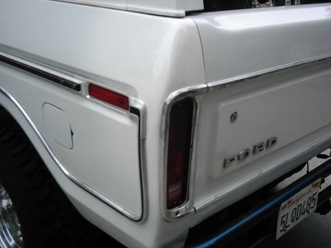 1978 Ford Bronco - Close-up of the rear corner of a white 1978 Ford Bronco, highlighting its taillight and chrome trim.