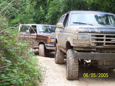 1987 Ford Bronco - Two 1987 Ford Broncos navigate a dirt path surrounded by trees. Date stamp shows 06/05/2005.