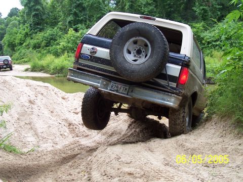 1987 Ford Bronco - This 1987 Ford Bronco navigates a sandy off-road trail, with a second vehicle visible in the background.