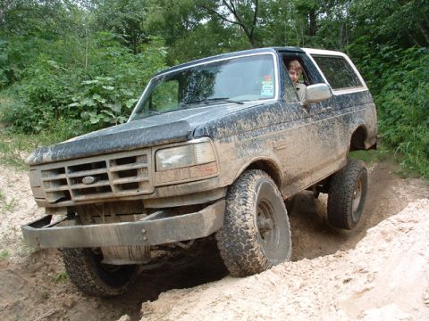1993 Ford Bronco - This 1993 Ford Bronco is navigating a challenging off-road trail covered in mud.