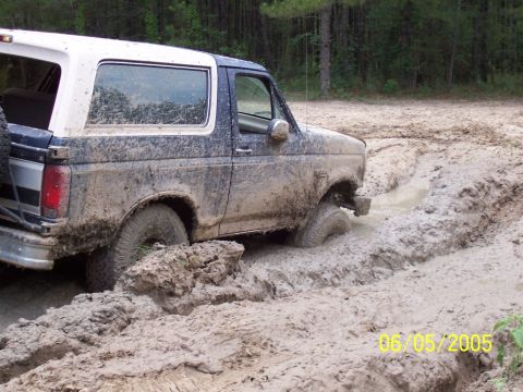 1987 Ford Bronco - This 1987 Ford Bronco is deep in the mud, with trees in the background.