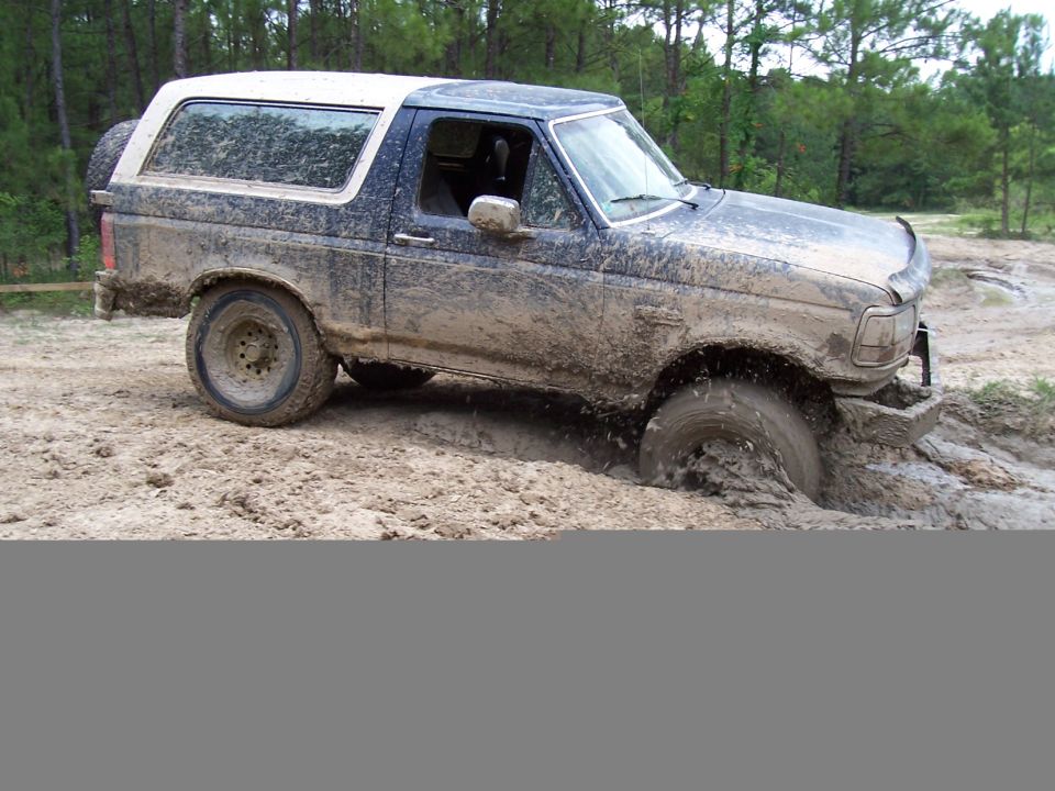 Mud-covered SUV stuck in mud, front right wheel submerged