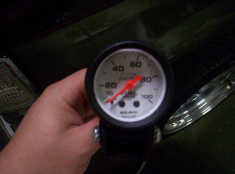 1989 Ford Bronco II - A hand holds a fuel gauge with a red needle indicating 70, with "FUEL" and "AUTO METER" visible on its face.