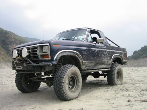1985 Ford Bronco - This lifted 1985 Ford Bronco is ready for off-road adventures, with large tires and a stance on a sandy terrain.